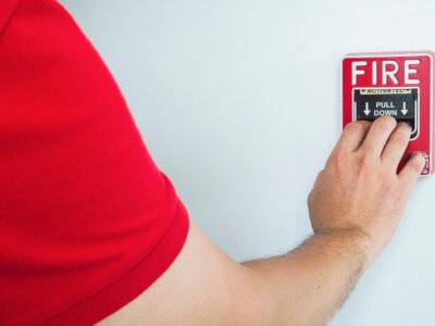a person wearing red shirt is pulling fire emergency button