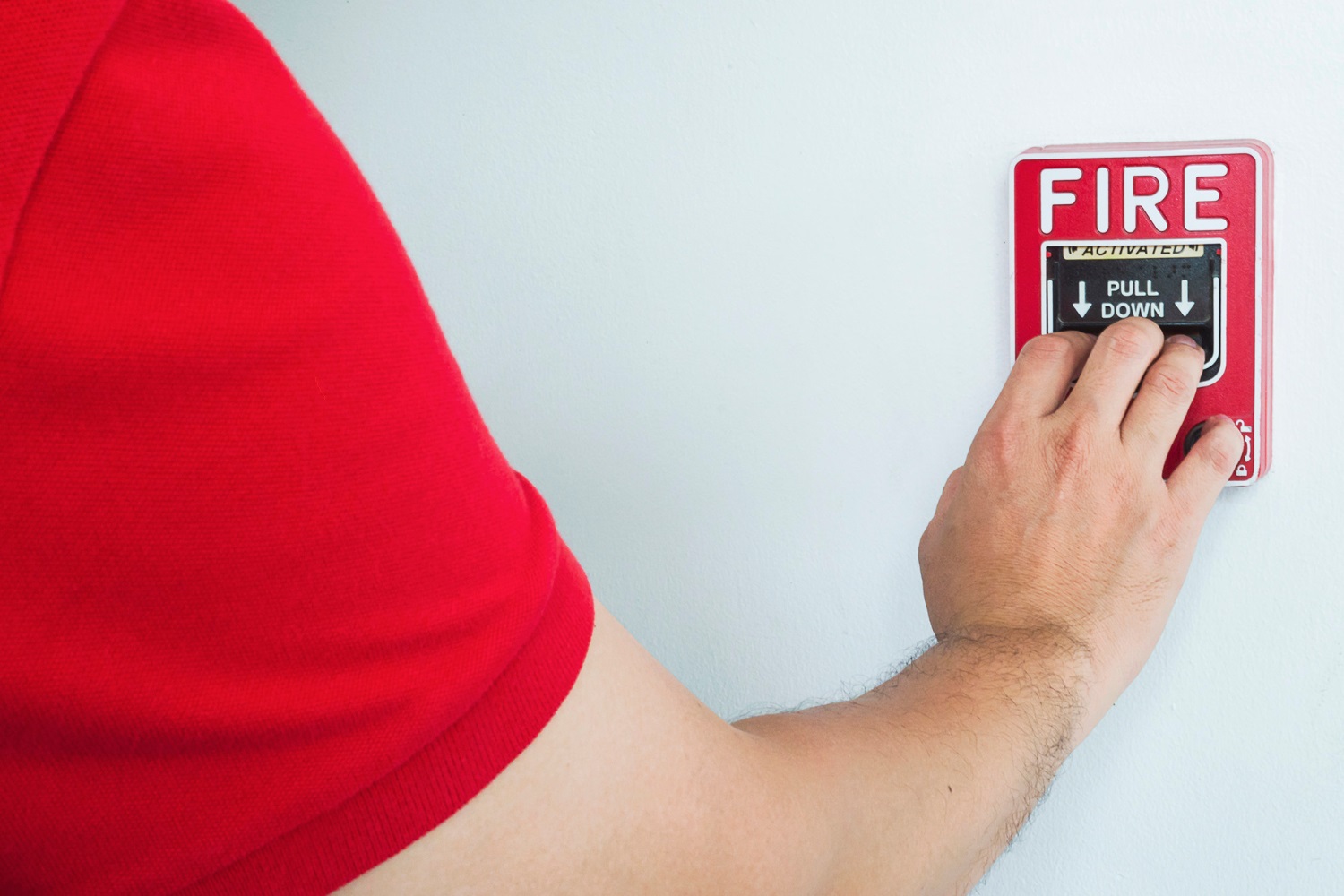 a person wearing red shirt is pulling fire emergency button