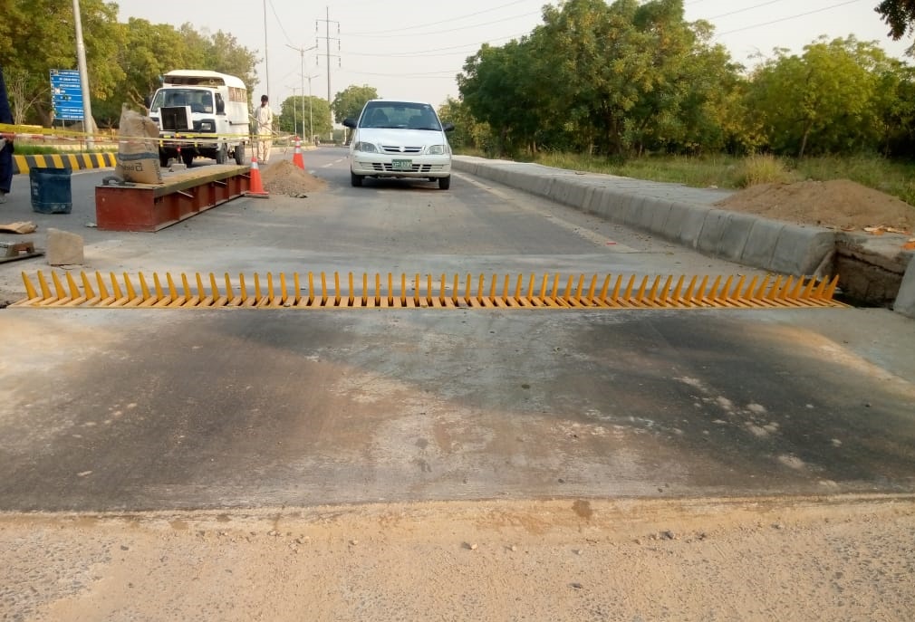 a car is about to cross a yellow tyre killer spikes from correct side of the machine